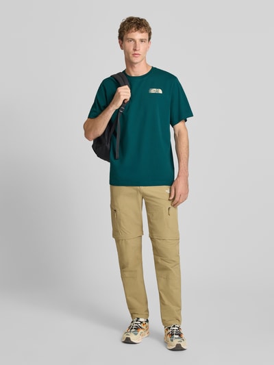 Männermodel trägt Relaxed Fit T-Shirt mit Logo-Print von The North Face in Grün aus reiner Baumwolle, Rundhalsausschnitt, Ganzkörperansicht von vorne.