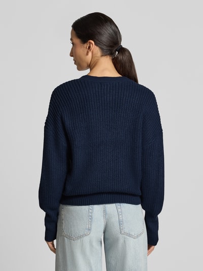 Männermodel trägt dunkelblauen kardigan rozpinany mit dekolt w serek Modell 'LEA' von VERO MODA, strukturierte grobe Stricktextur, Ganzkörperansicht Rückansicht.