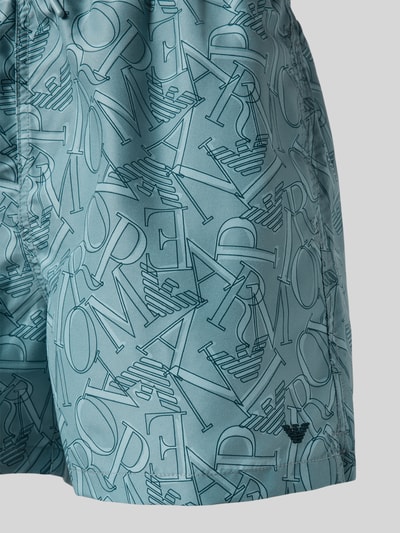 Männermodel trägt Regular Fit Shorts mit Allover-Logo-Print von Emporio Armani, elastischer Bund mit Tunnelzug, Nahaufnahme Oberschenkel.