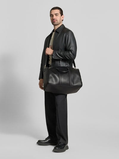 Männermodel trägt Weekender mit abnehmbarem Schulterriemen von CK Calvin Klein in Schwarz, glatte Textur, Ganzkörperansicht von vorne.