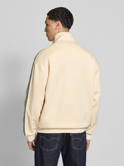 Männermodel trägt Relaxed Fit Sweatjacke mit Kontraststreifen Modell 'RIBER' von Only & Sons, Optik: Unifarben, Passform: Relaxed-Fit, Verschluss: Reißverschluss, Applikation: Kontraststreifen, Kragenform: Stehkragen, Ärmelform: Langarm, Ärmelabschluss: Gerippt, Rumpfabschluss: Gerippt, Taschen: Seitliche Eingrifftaschen, Materialverarbeitung: Sweat, cremefarben, glatte Struktur, Ganzkörperansicht Rückansicht.
