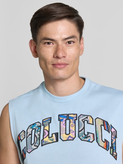 Männermodel trägt Regular Fit Tanktop mit Label-Stitching von COLUCCI aus hellblauer Baumwolle mit buntem Logo, Nahaufnahme Oberkörper.
