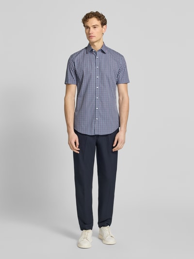 Männermodel trägt Slim Fit Business-Hemd aus katoen met kentkraag van Jake*s, blauw geruit, knoopsluiting, 1/2-mouwen, Ganzkörperansicht van voren.