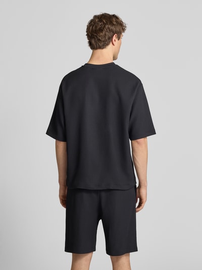 Männermodel trägt Regular-Fit T-Shirt in Plissee-Optik von REVIEW, schwarzer Material-Mix mit Stretch-Anteil, Rückansicht Ganzkörperansicht.