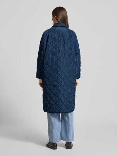 Vrouwenmodel draagt Regular Fit Steppmantel met Logo-Details van Tommy Hilfiger in effen donkerblauw met ruitvormige stiksels, lange mouwen, opgestikte zakken; Ganzkörperansicht Rückansicht.