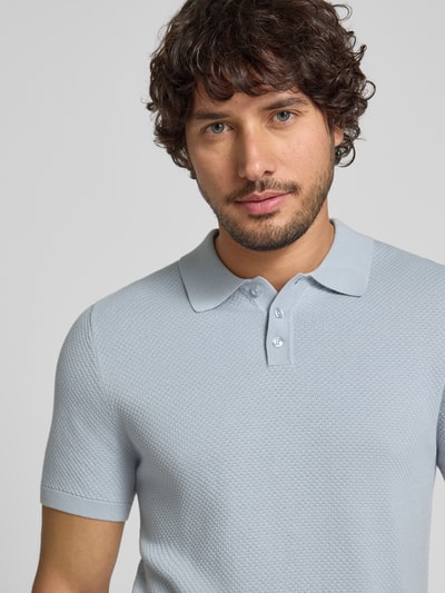 Männermodel trägt Slim Fit Poloshirt Modell 'Triton' von Drykorn aus reiner Baumwolle, Strukturmuster, hellblau, Nahaufnahme Oberkörper.