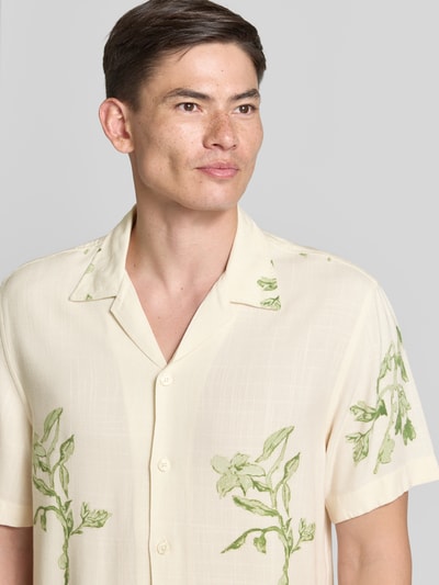 Männermodel trägt Regular Fit Freizeithemd aus reiner Viskose Modell 'TERRY' von SELECTED HOMME, cremefarben mit grünem Pflanzenmuster, Nahaufnahme Oberkörper, Herren Freizeithemd von SELECTED HOMME.