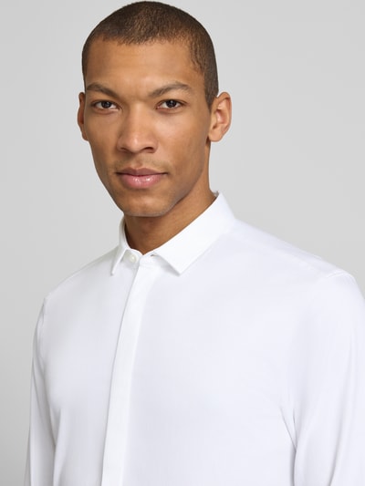Männermodel trägt Slim Fit Businesshemd aus Baumwoll-Mix Modell 'KETRAN' von HUGO, Optik: Unifarben, Kentkragen, Nahaufnahme Oberkörper.