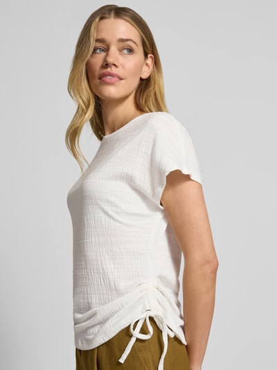 Modelka kobieca ma na sobie Regular Fit T-Shirt mit Viskose-Anteil od Apricot, biała tkanina z motywem strukturalnym, ozdobne troczki, okrągły dekolt, długość pleców w rozmiarze S: 59 cm, zdjęcie całej sylwetki z przodu.