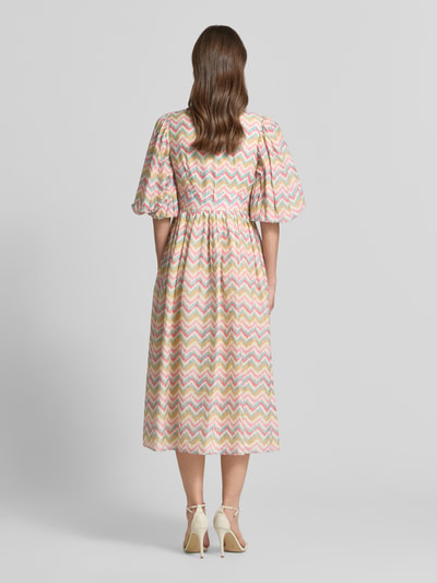 Frauenmodel trägt Cocktailkleid im Allover-Look mit 3/4-Arm von LACE & BEADS, A-Linie, Midikleid, Muster in Pastelltönen, Ganzkörperansicht Rückansicht.