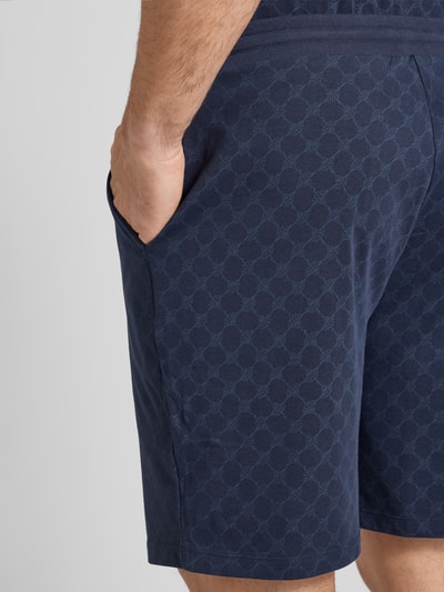 Männermodel trägt Shorts aus Baumwolle mit Logo-Muster von JOOP! Collection in Dunkelblau, Regular-Fit, Nahaufnahme Oberschenkel.