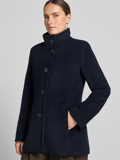 Modelka nosi kurtkę 'Jacke mit Stehkragen und Eingrifftaschen' od FUCHS SCHMITT, granatowa, Mieszanka materiałów z dodatkiem wełny, Linia a, stójka, listwa guzikowa, wpuszczane kieszenie, Długość tyłu w rozmiarze 36: 73 cm, Szerokość ramion w rozmiarze 36: 37 cm, Szerokość w rozmiarze 36: 48 cm, Długość rękawów w rozmiarze 36: 64 cm, widok całej sylwetki z przodu
