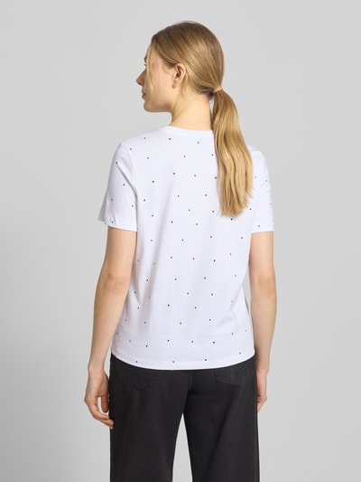 Kobiece modelka ma na sobie Shaped Fit T-Shirt aus reiner Baumwolle Modell 'PAULINA AOP' von Vero Moda, biała koszulka z nadrukiem allover, krótki rękaw, okrągły dekolt, jersey, widok całej sylwetki z tyłu.