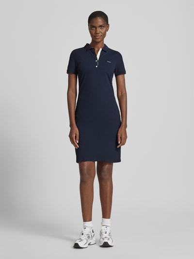 Frauenmodel trägt Knielanges Polokleid mit Label-Stitching von Gant in Dunkelblau, Baumwoll-Elasthan-Mix, Ganzkörperansicht von vorne.