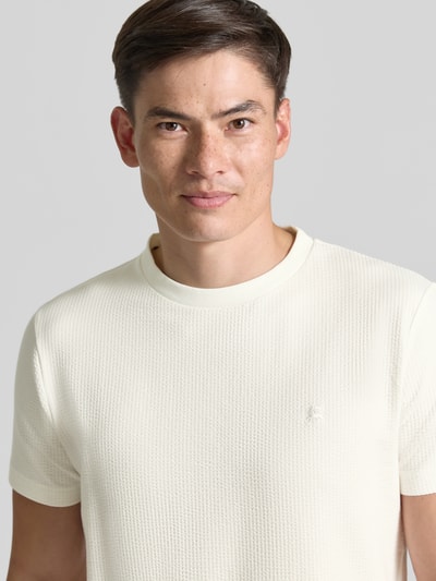 Männermodel trägt T-Shirt mit Strukturmuster und Logo-Stitching von Lerros in Creme mit Rundhalsausschnitt, Baumwoll-Mix mit Stretch-Anteil, Regular-Fit, Nahaufnahme Oberkörper.