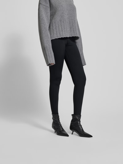 Frauenmodel trägt Leggings mit elastischem Logo-Bund von black palms, schwarzer Material-Mix mit Stretch-Anteil, körpernaher Schnitt, Ganzkörperansicht von vorne.