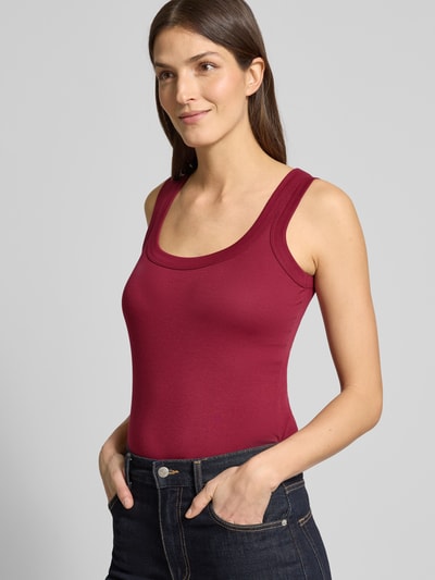 Modelka nosi Tanktop mit geripptem Rundhalsausschnitt von Marc Cain, krój slim fit, kolor bordowy, długość tyłu w rozmiarze 36: 45 cm, zdjęcie w półzbliżeniu z przodu.