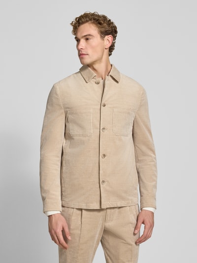 Męski model nosi Slim Fit Hemdjacke aus Cord von MCNEAL, mieszanka bawełny i elastanu, kołnierzyk typu kent, kieszenie na piersi, listwa guzikowa, sztruks, kolor beżowy, długość tyłu w rozmiarze M: 70 cm, Ganzkörperansicht von vorne.