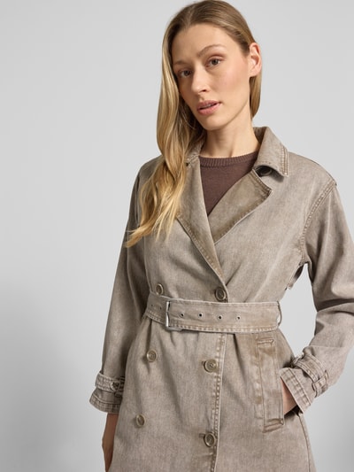 Modelka kobieca ma na sobie dwurzędowy płaszcz z paskiem Modell 'HERA' od khujo, bawełna, krój prosty, denim, zbliżenie górnej części ciała. Długość pleców w rozmiarze S: 103 cm, szerokość ramion w rozmiarze S: 43 cm, szerokość klatki piersiowej w rozmiarze S: 48 cm, długość rękawa w rozmiarze S: 55 cm.