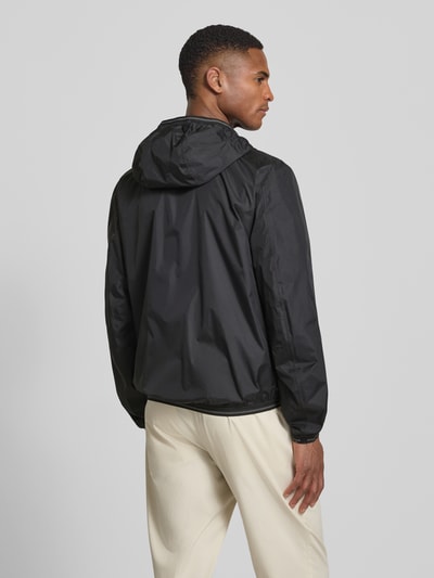 Männermodel trägt Jacke mit Label-Patches Modell 'Dodge' von Blauer Usa in Schwarz, Gerader-Schnitt, Kapuze, Rückenansicht, Ganzkörperansicht Rückansicht.