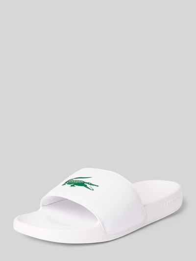 Produktfoto, Badeschuhe mit Logo Print Modell 'SERVE SLIDE' von Lacoste, Optik: Unifarben, Schuhspitze: Abgerundet, Absatzform: Flach, Applikation: Logo-Print, Verschluss: Schlupf/offen, strukturierte Sohle, weiß mit grünem Logo, glatte Struktur