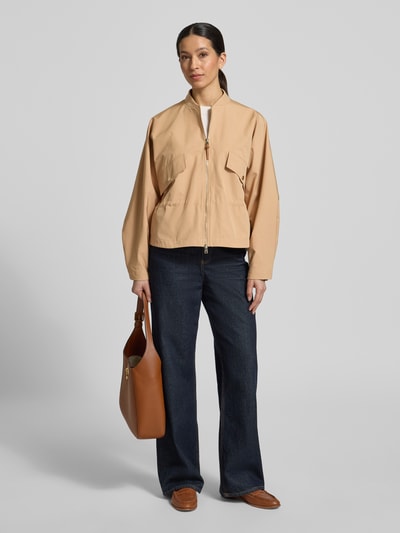 Frauenmodel trägt Jacke mit Zweiwege-Reißverschluss von Rich & Royal in Beige aus Baumwoll-Mix mit Pattentaschen, Regular-Fit, Stehkragen, Ganzkörperansicht von vorne. Rückenlänge 58 cm, Schulterbreite 47 cm, Brustweite 54 cm, Ärmellänge 57 cm bei Größe 36.
