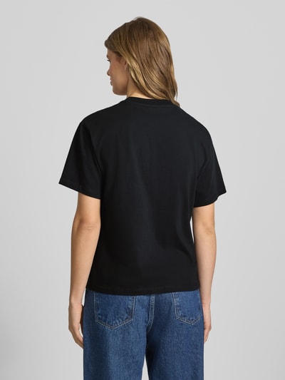 Frauenmodel trägt Carhartt Work In Progress Damen T-Shirt mit Label-Stitching aus reiner Bio-Baumwolle, Relaxed-Fit, Rundhalsausschnitt, Rückenlänge 64 cm, Ganzkörperansicht Rückansicht.