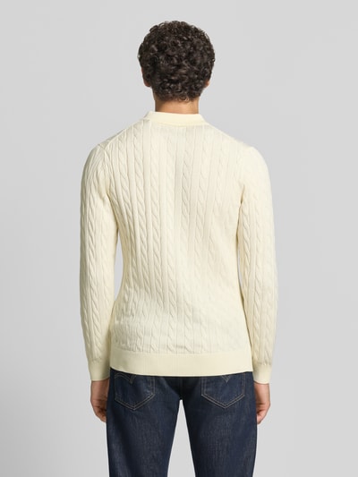 Männermodel trägt Regular Fit Pullover aus reiner Baumwolle von GANT in Creme mit Zopfmuster, strukturierte Oberfläche, Ganzkörperansicht Rückansicht.