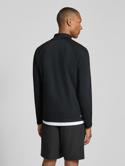 Męski model nosi Regular Fit Sport-Langarmshirt mit Ultra-Dry-Technologie od Lacoste, czarny kolor, sportowa bluzka z długim rękawem, widok całej sylwetki z tyłu, kontekst: bluzka sportowa męska od Lacoste Sport.
