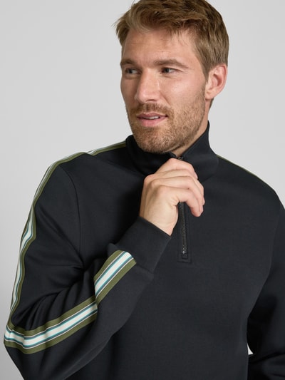 Männermodel trägt Sweatshirt aus Baumwoll-Mix von Paul Smith, dunkle Farbe, Streifendetails, lockere Passform, Nahaufnahme Oberkörper. Rückenlänge Größe M: 68 cm, Ärmellänge: 70 cm, Troyer-Kragen, elastische Abschlüsse.