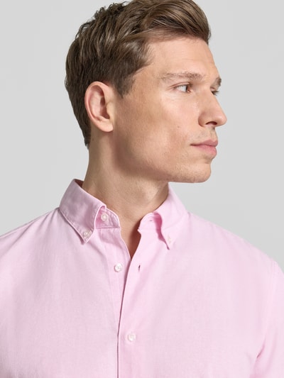 Mężczyzna nosi Slim Fit Freizeithemd aus reiner Baumwolle von MCNEAL w jasnoróżowym kolorze, z kołnierzykiem button-down, długim rękawem, zaokrąglonym dołem, 100% bawełna, krój slim fit, widoczna cała listwa guzikowa, Szerokość w rozmiarze M: 44 cm, rękaw: 65 cm, długość: 74 cm; zbliżenie na górną część tułowia