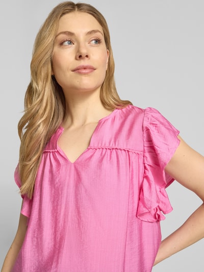 Frauenmodel trägt Bluse aus Viskose-Mix mit Rüschen Modell 'HETTA' von ICHI, Farbe Pink, Serafino-Ausschnitt, Nahaufnahme Oberkörper.