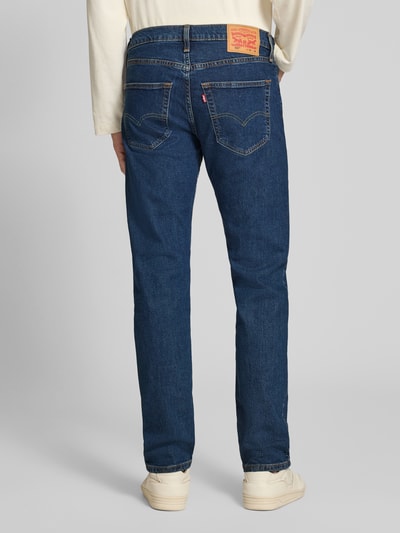 Männermodel trägt blaue Tapered Fit Jeans aus Baumwoll-Mix Modell '502®' von Levi's®, Herren Tapered Fit Jeans, Ganzkörperansicht Rückansicht.