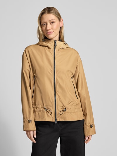 Modelka prezentuje kurtkę 'Jacke mit Zweiwege-Reißverschluss' od Fuchs Schmitt w kolorze beżowym, krój regular fit, kaptur z tunelem, kieszenie zapinane na zamek błyskawiczny, długość tyłu w rozmiarze 36: 67 cm, szerokość ramion w rozmiarze 36: 53 cm, szerokość w klatce piersiowej w rozmiarze 36: 59 cm, długość rękawów w rozmiarze 36: 57 cm, widok z przodu w ujęciu całej sylwetki.