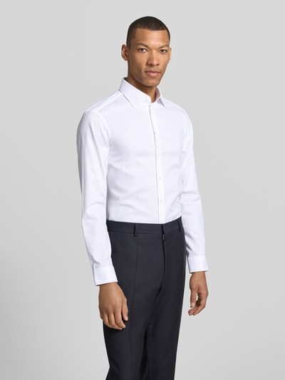 Männermodel trägt Regular Fit Business-Hemd mit Kentkragen von Christian Berg Men aus Reine Baumwolle, weiß, Knopfleiste, Sportmanschetten, abgerundeter Saum; Rückenlänge 78 cm, Schulterbreite 43 cm, Ärmellänge 65 cm, Ganzkörperansicht von vorne.
