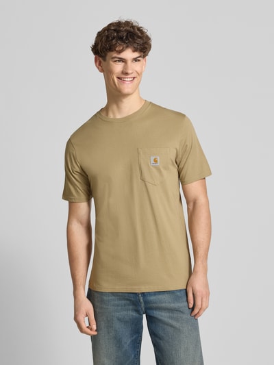 Männermodel trägt Regular Fit T-Shirt mit Logo-Patch von Carhartt Work In Progress in Beige, Baumwolle, Rundhals, Brusttasche, Ganzkörperansicht von vorne.