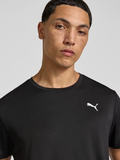 Männermodel trägt schwarzes Regular Fit Sport-T-Shirt mit Logo-Print Modell 'TAD Essential' von PUMA, Nahaufnahme Oberkörper, Herren Sport-T-Shirt von PUMA Performance.