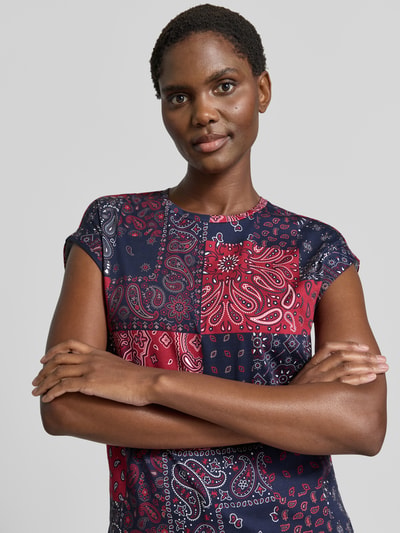 Kobiece model nosi Damski t-shirt z bawełny, krój taliowany, okrągły dekolt, opadające ramiona, stałe zakończenia rękawów, Christian Berg Woman, długość tyłu w rozmiarze S: 55 cm, wzór patchwork, przód, zbliżenie na górną część ciała.
