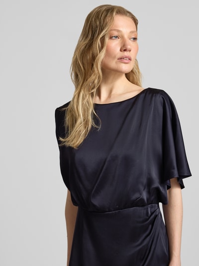 Frauenmodel trägt Schimmerndes Midikleid im One-Shoulder-Look von Comma, Material-Mix mit Viskose-Anteil, gerader Schnitt, Rundhalsausschnitt, schimmernde Optik, Nahaufnahme Oberkörper.