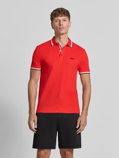 Męski model nosi koszulkę polo Regular Fit Poloshirt aus reiner Baumwolle model 'PADDY' od BOSS Green, kolor czerwony, gładka tekstura, całkowity widok z przodu.