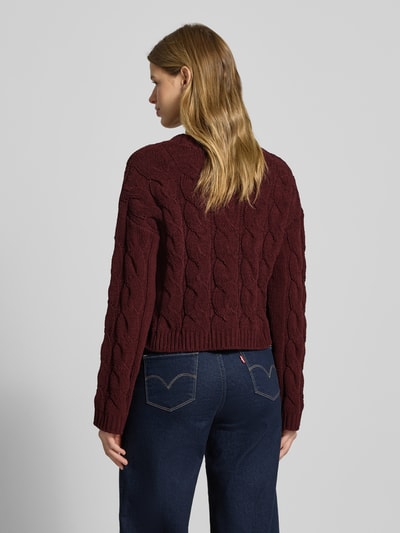Frauenmodel trägt Regular Fit Strickpullover mit Zopfmuster Modell 'ELLY' von Only in bordeaux, unifarben, gerippte Abschlüsse, Ganzkörperansicht Rückansicht.