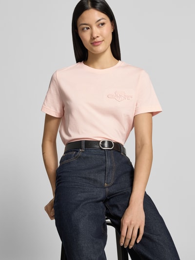 Vrouwenmodel draagt lichtroze regular fit t-shirt van puur katoen van GANT, Regular Fit T-Shirt aus reiner Baumwolle van GANT, close-up bovenlichaam.