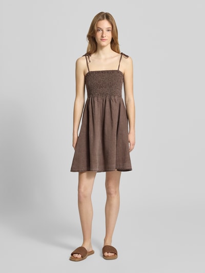 Frauenmodel trägt Minikleid mit Smok-Detail Modell 'Oregon' von Noisy May aus reiner Baumwolle, taillierte Passform, braune Farbe, Ganzkörperansicht von vorne.