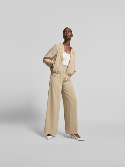 Frauenmodel trägt Blouson mit Reißverschluss von Joseph, Material-Mix, lockere Passform, Stehkragen, Eingrifftaschen, Rückenlänge 60 cm, Brustweite 40 cm, Ärmellänge 62 cm, sandfarben mit glatter Textur, Ganzkörperansicht von vorne.