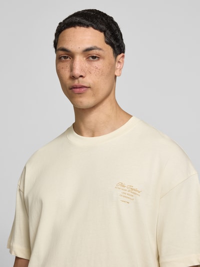 Männermodel trägt T-Shirt mit Rundhalsausschnitt von Jack & Jones in Creme mit Print, Reine Baumwolle, Regular-Fit, Nahaufnahme Oberkörper.