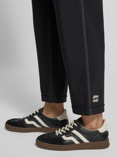 Mannelijk model draagt stoffen broek met elastische band van Marc Cain, materiaalmix met stretch, los model, steekzakken, detailopname.