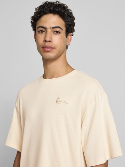 Männermodel trägt Oversized T-Shirt mit Logo-Stitching von KARL KANI aus Reine Baumwolle, Oversized-Fit, Rundhalsausschnitt, Nahaufnahme Oberkörper. Rückenlänge bei Größe M: 65 cm.