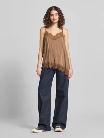 Frauenmodel trägt Relaxed Fit Top aus Viskose-Mix Modell 'Tami' von OH APRIL in Braun mit Spitzenbesatz und Spaghetti-Trägern, Ganzkörperansicht von vorne.