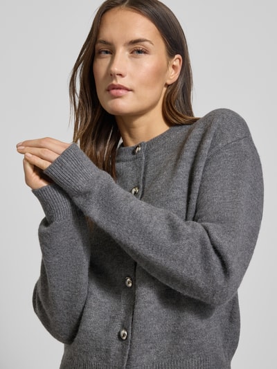 Frauenmodel trägt Cardigan mit Rundhalsausschnitt Modell 'FELIPE' von Mango, grauer Material-Mix mit Woll-Anteil, Knopfverschluss, Nahaufnahme Oberkörper.