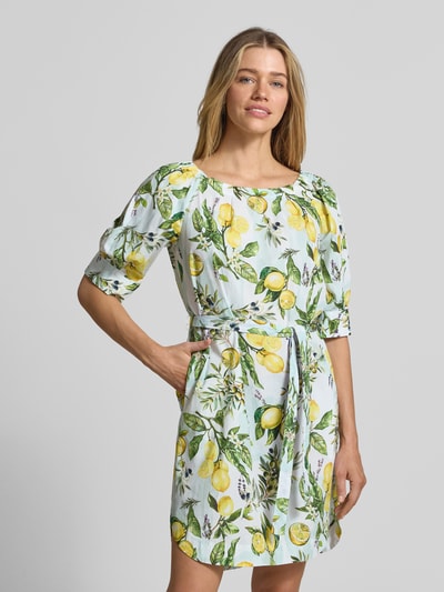 Frauenmodel trägt Minikleid mit Bindegürtel von Marc Cain, weiß mit gelbem Zitronen-Print, Baumwolle, gerader Schnitt, Nahaufnahme Oberkörper.